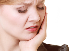 young woman holding cheek suffering from toothaches