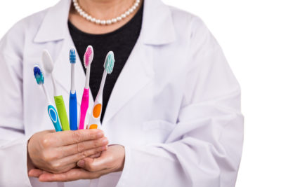 dentist holding different types of toothbrushes