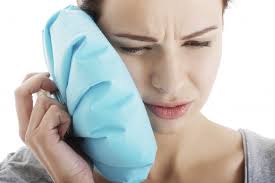 woman holding ice bag to cheek due to toothache