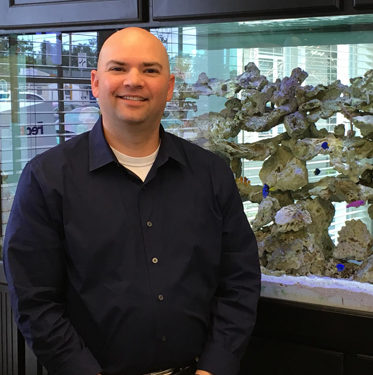 dr. sherman smiling in front of fish tank